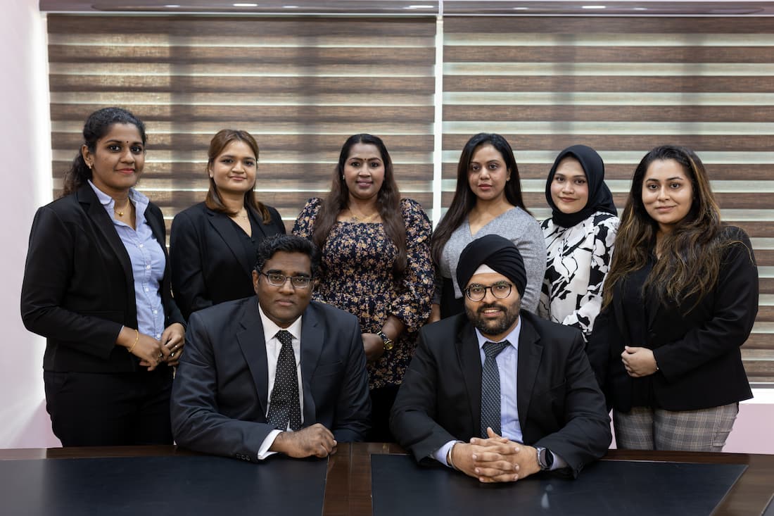 2 male lawyers sitting down and 6 women lawyers standing behind